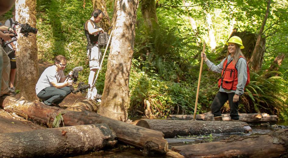Wildlife biologist being filmed standing in a stream 